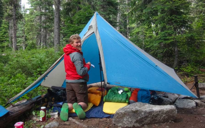 a person smiles as they set up a shelter for the night